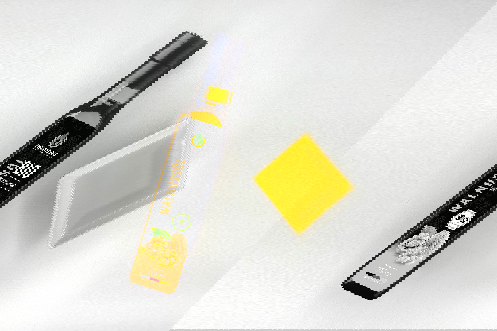 Kräuterland Bio Walnussöl 250 ml kaltgepresst in Glasflasche neben Schälchen mit dem gleichen goldgelben Öl zur Veranschaulichung der Farbe