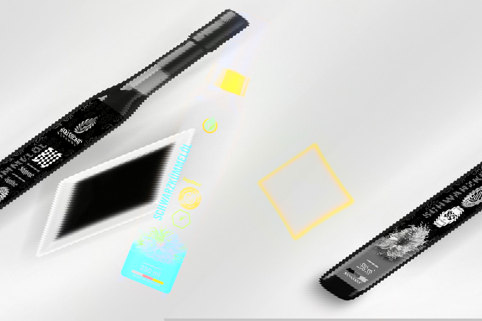 Kräuterland Bio Schwarzkümmelöl 250 ml kaltgepresst und ungefiltert in Glasflasche neben Schälchen mit dem gleichen dunklen Öl zur Veranschaulichung der natürlichen Farbe