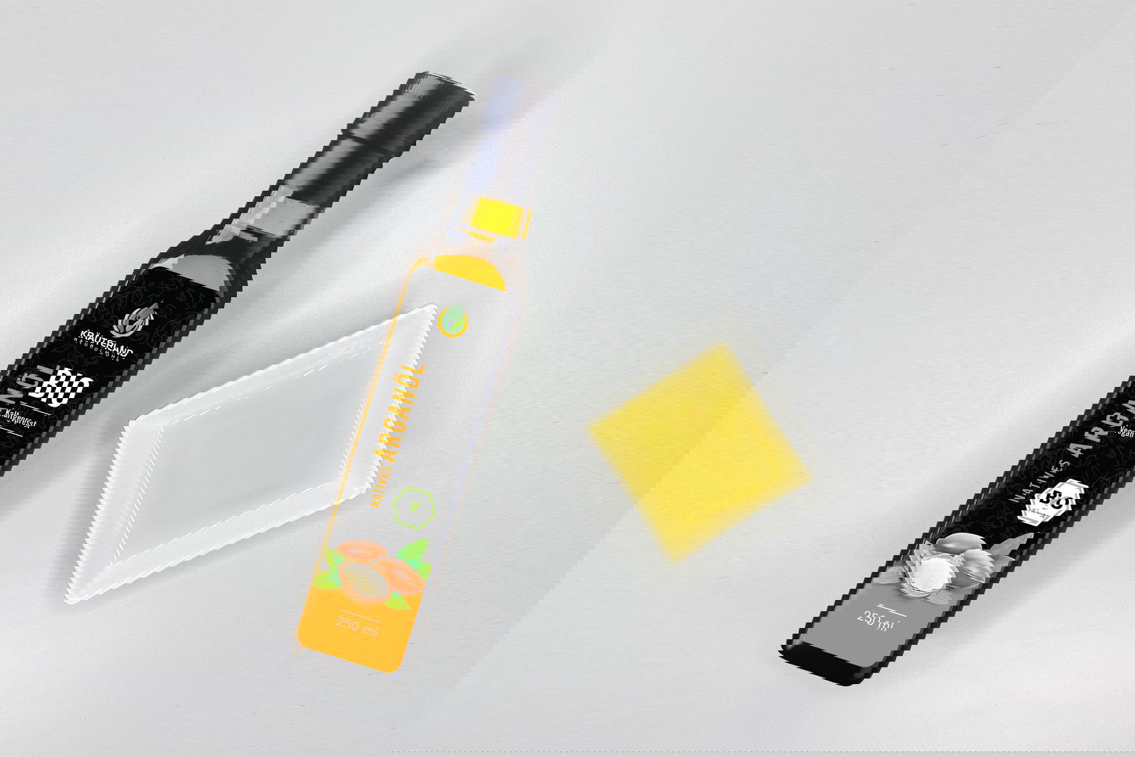 Kräuterland Bio Arganöl kaltgepresst in Glasflasche neben Schälchen mit dem gleichen goldgelben Öl zur Veranschaulichung