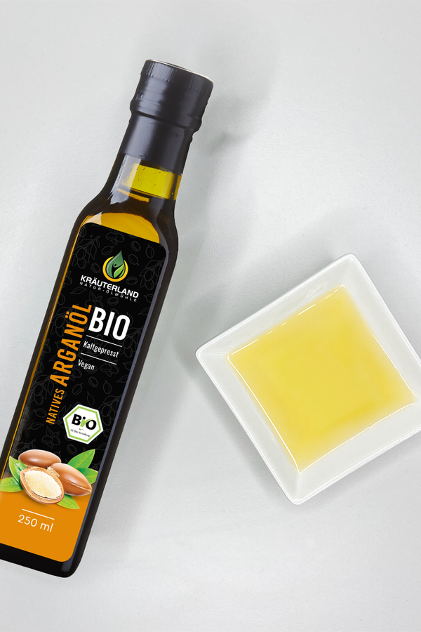 bio-arganoel-produkt Kräuterland Bio Arganöl kaltgepresst in Glasflasche neben Schälchen mit dem gleichen goldgelben Öl zur Veranschaulichung