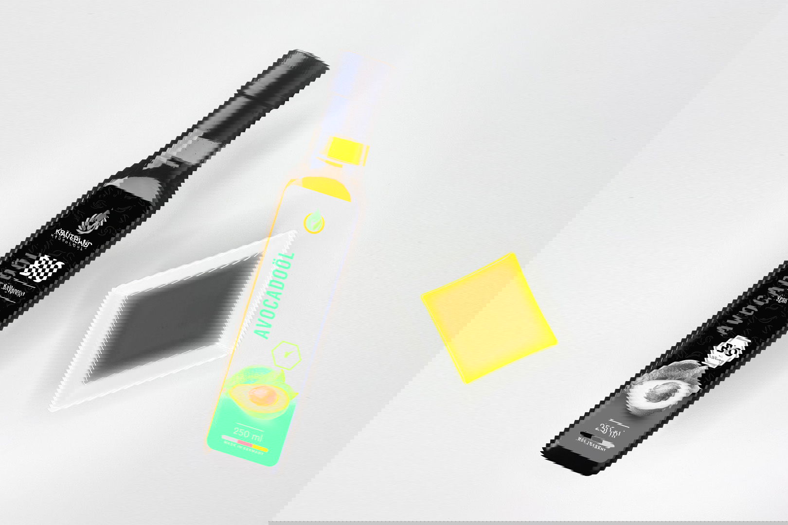 Kräuterland Bio Avocadoöl 250 ml kaltgepresst in Glasflasche neben Schälchen mit dem gleichen grünlich-goldenen Öl zur Veranschaulichung der Farbe