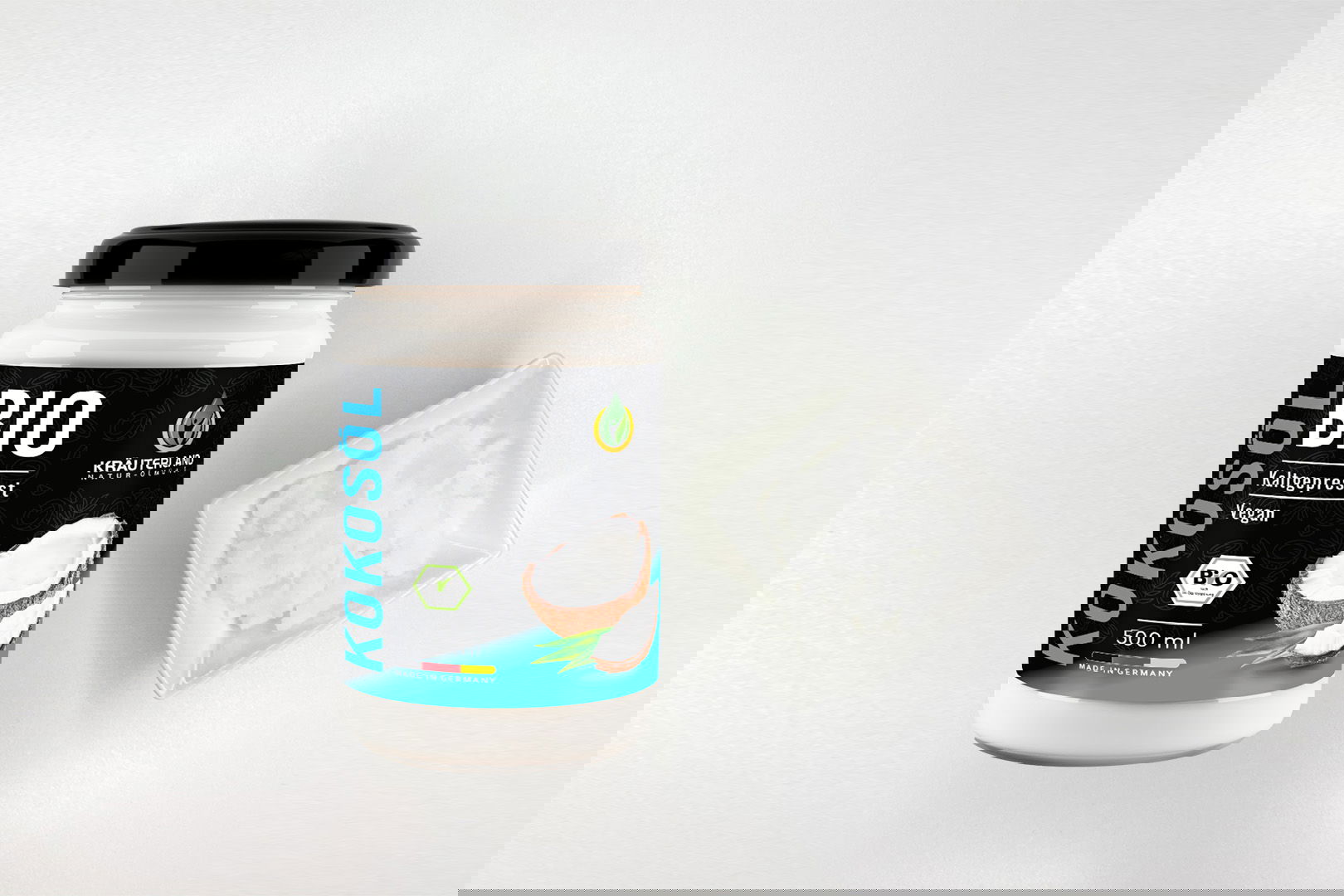 Kräuterland Bio Kokosöl 500 ml kaltgepresst im Glas neben Schälchen mit festem, weißem Kokosöl bei Zimmertemperatur