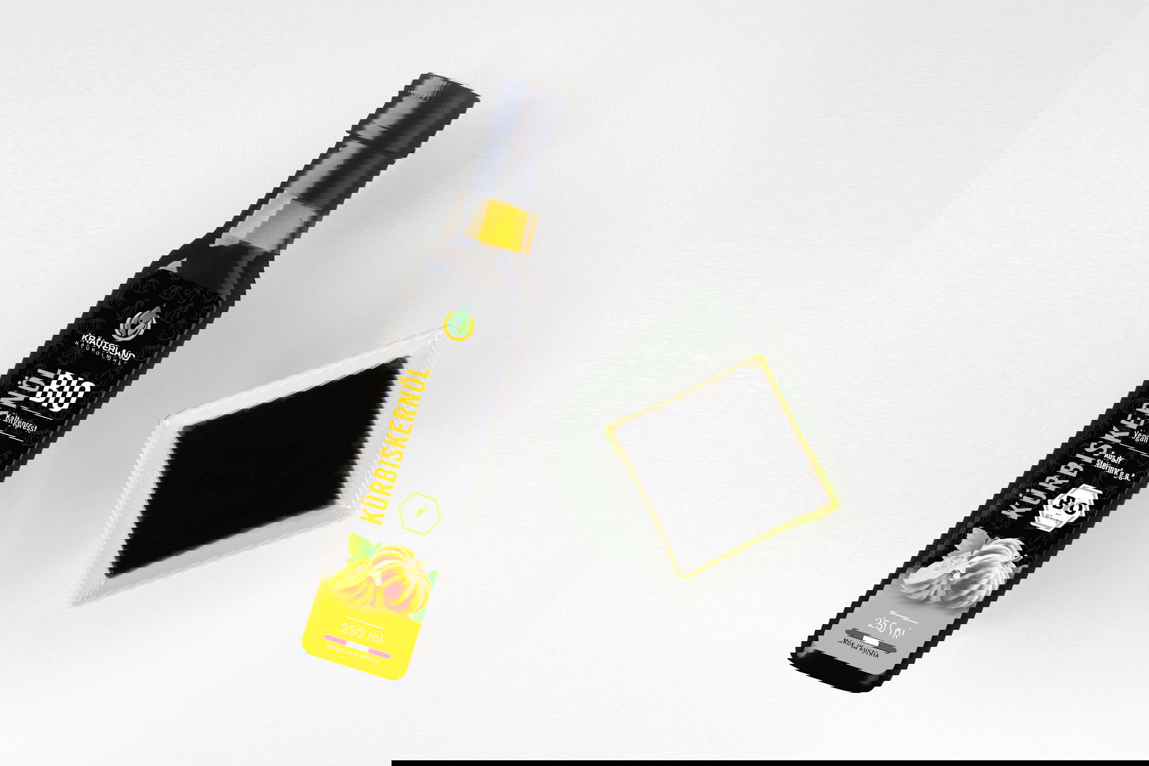 Kräuterland Bio Kürbiskernöl 250 ml kaltgepresst in Glasflasche neben Schälchen mit dem gleichen dunkelgrünen Öl zur Veranschaulichung der Farbe