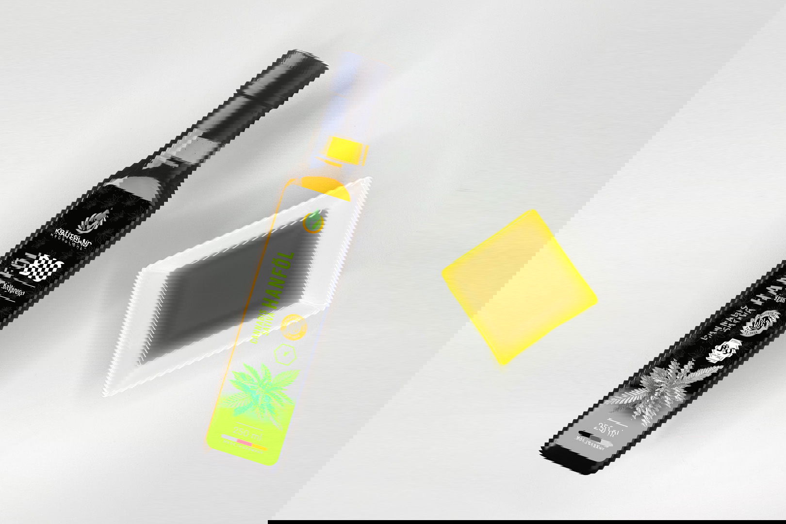 Kräuterland Bio Hanföl 250 ml kaltgepresst in Glasflasche neben Schälchen mit dem gleichen grünlich-goldenen Öl zur Veranschaulichung der Farbe