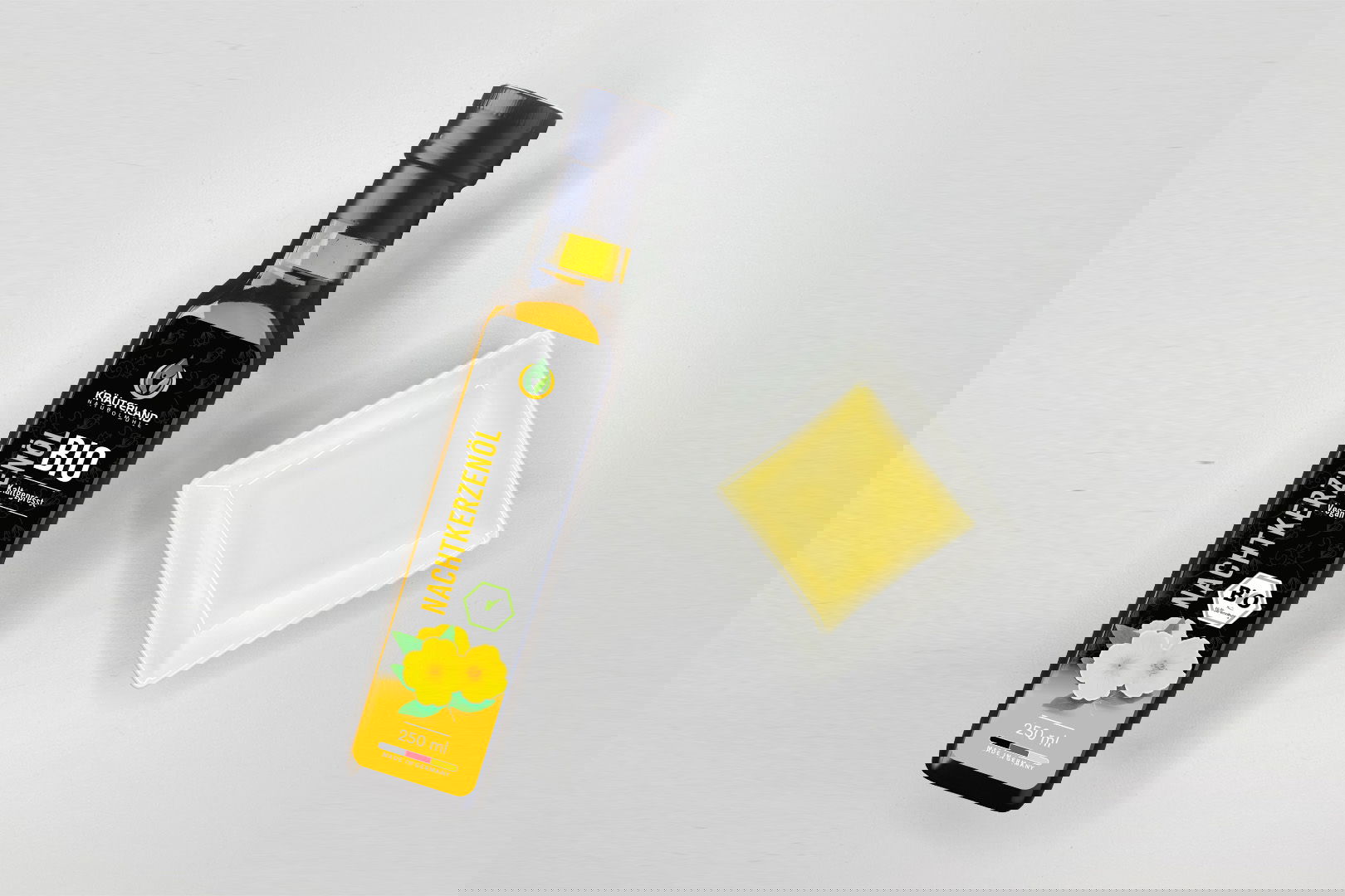 Kräuterland Bio Nachtkerzenöl 250 ml kaltgepresst in Glasflasche neben Schälchen mit dem gleichen goldgelben Öl zur Veranschaulichung der Farbe